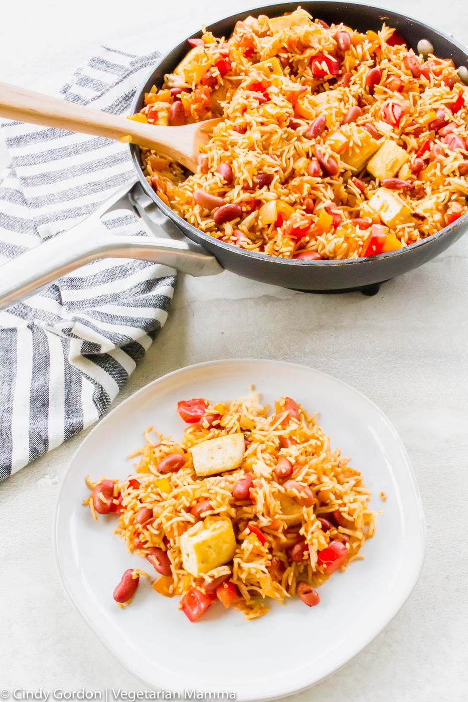 Overhead picture of tofu with rice in a skillet and some on a white plate