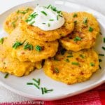 Zucchini Fritters atop white plate with red cloth beside plate