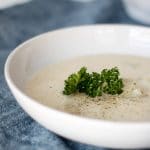 Rustic Potato soup in round white bowl atop black cloth