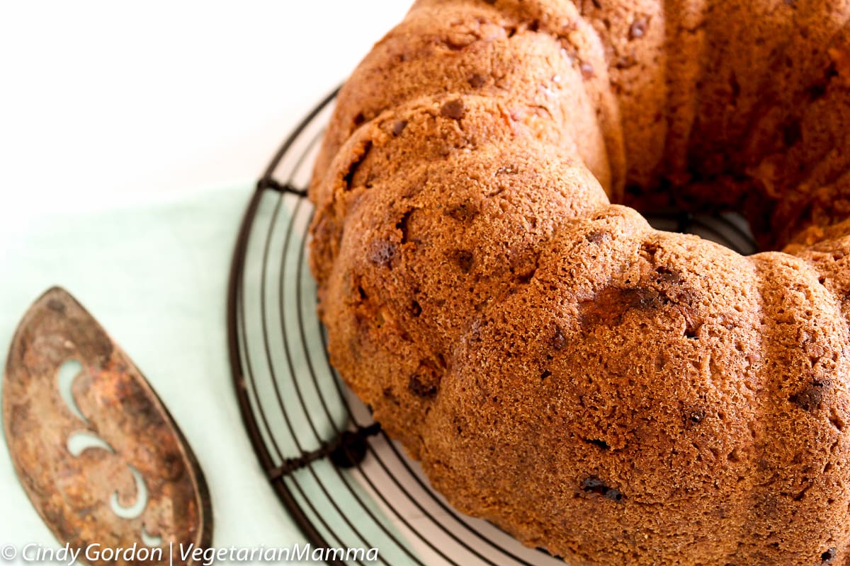 Easy gluten free apple bundt cake on a round wire rack. A vintage cake server is next to it. 