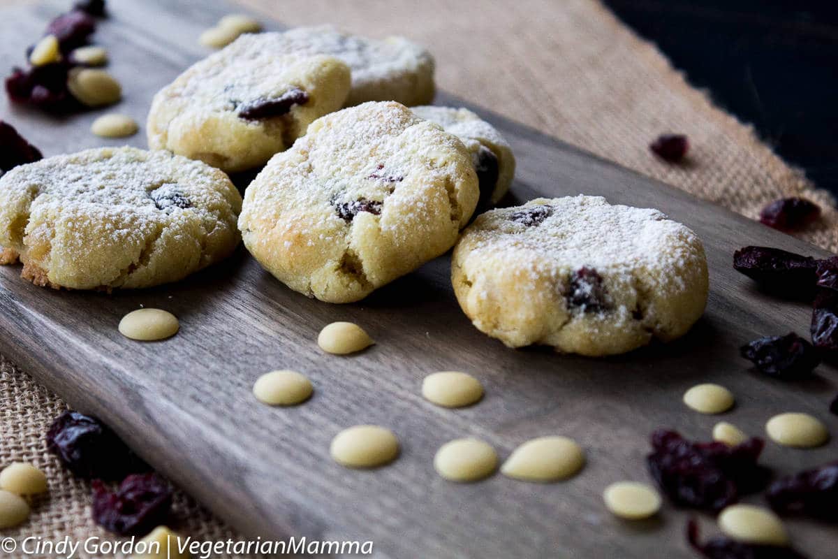 Vegan Lemon Cranberry cookies on cutting board with dried cranberries and dairy free chocolate around them