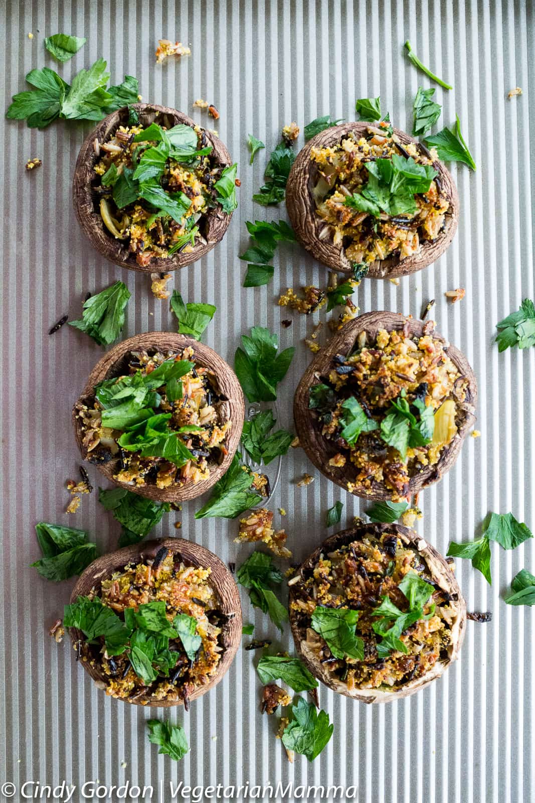 Six Gluten Free, Vegetarian Wild Rice Stuffed Mushrooms on a cookie sheet topped with parsley