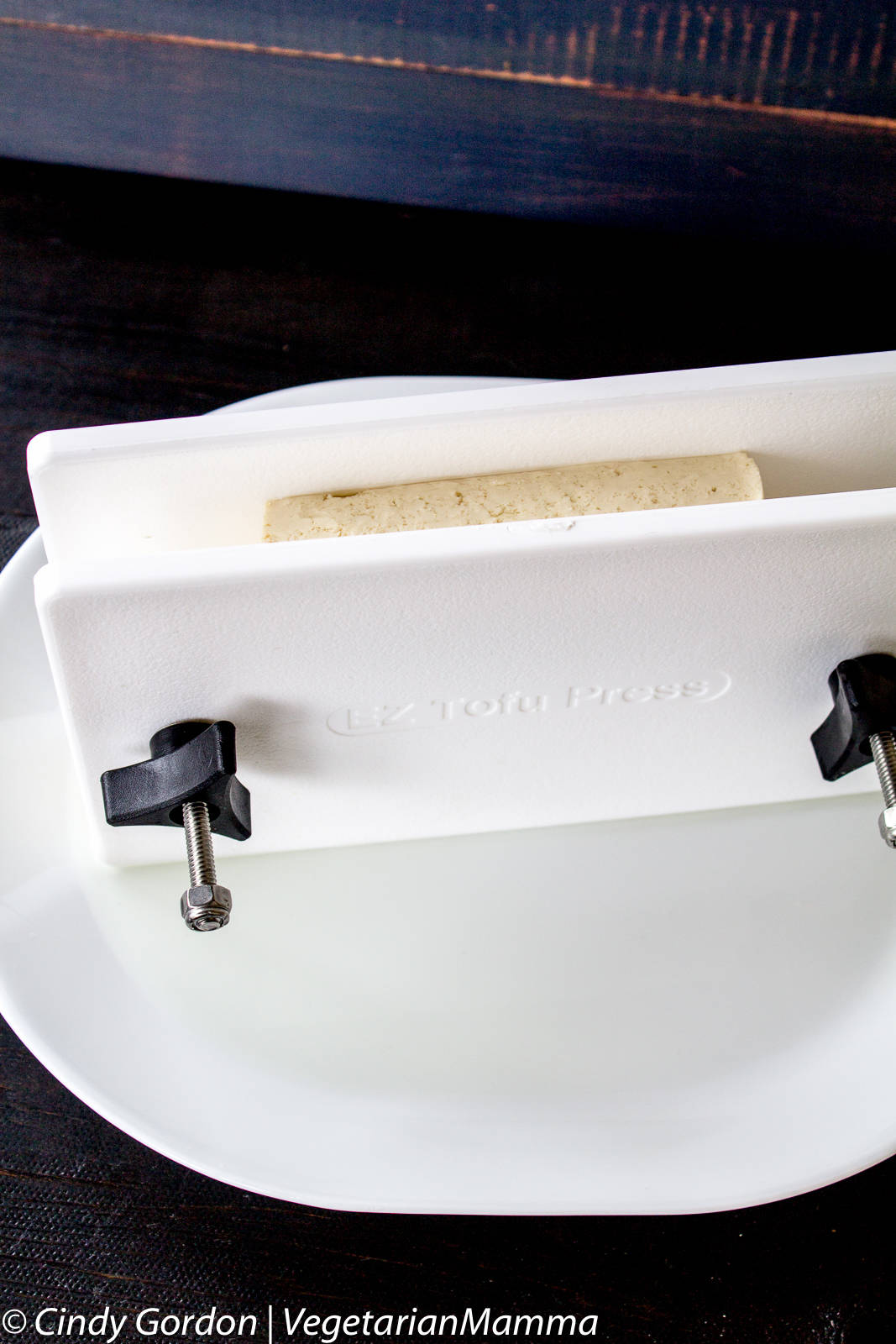 A white tofu press with a block of off white colored tofu inside