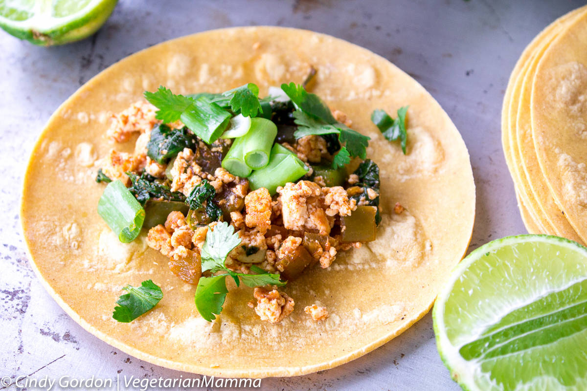 scrambled tofu with cilantro and diced green onions on a light brown corn tortilla 