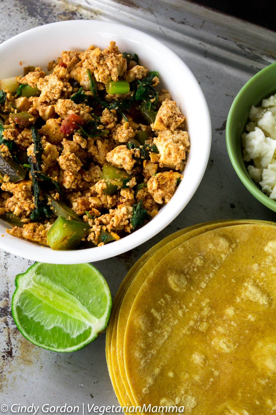 A white bowl with brown tofu crumbles scrambled with vegetables and herbs 