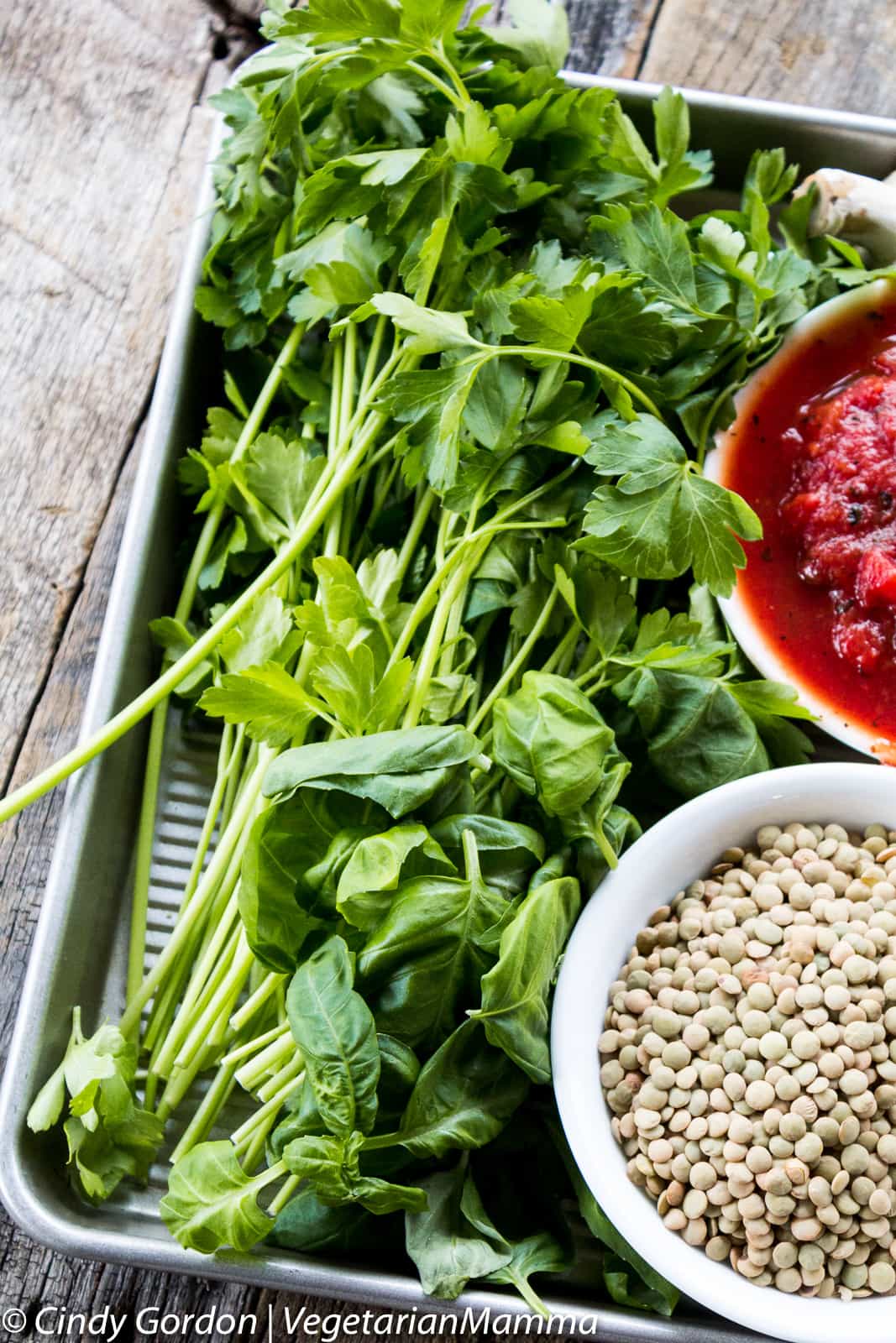 fresh herbs, canned tomatoes, and lentils on a baking sheet