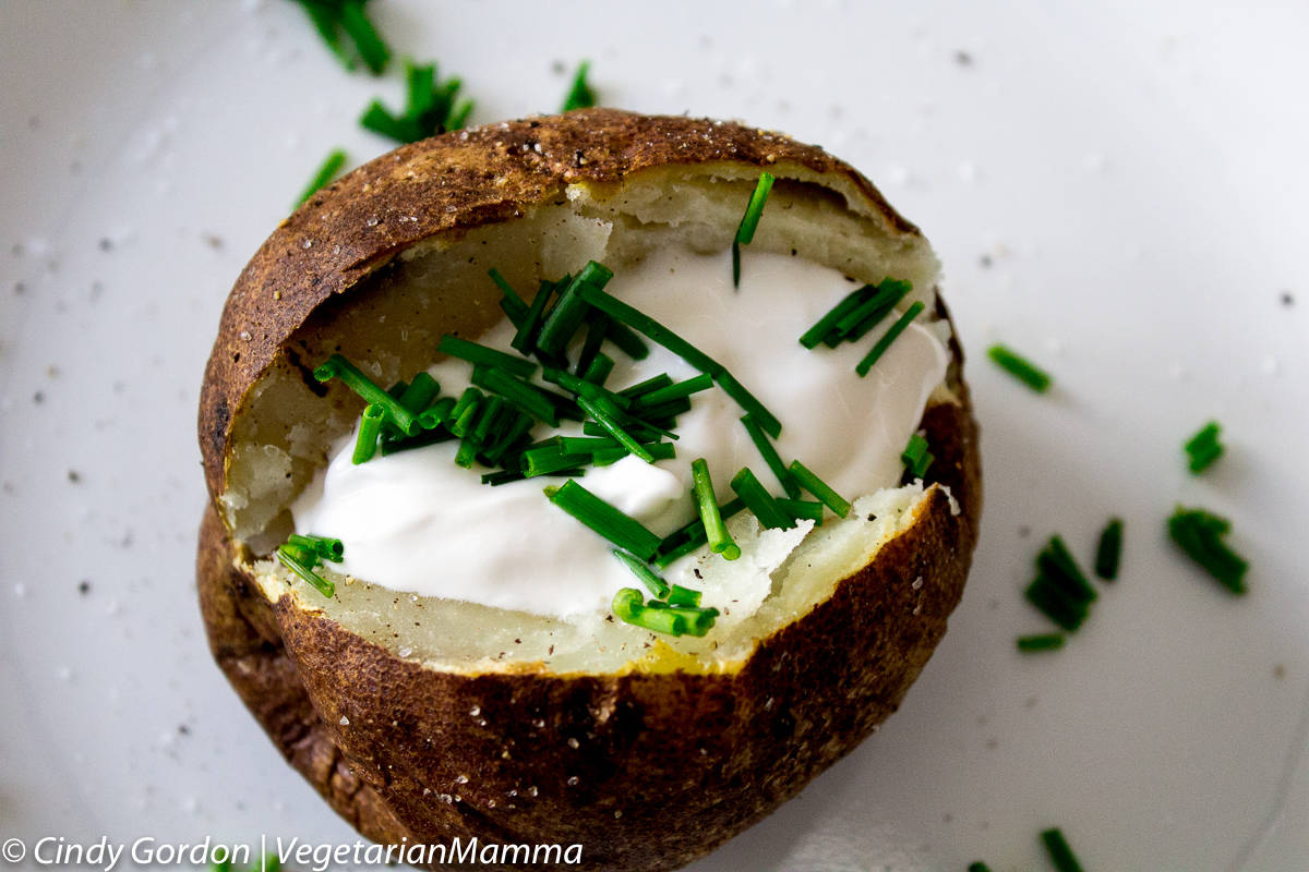 Air fryer baked potato topped with sour cream and chives