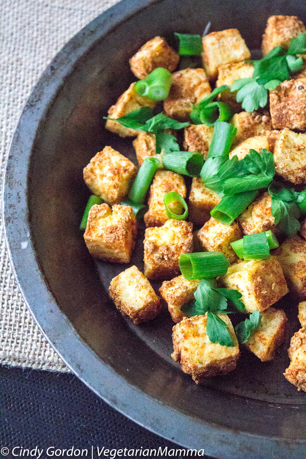 air fryer tofu bites topped with chives in a pie dish