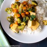 Curry Tofu with Broccoli and Rice in white plate atop black wooden pallet