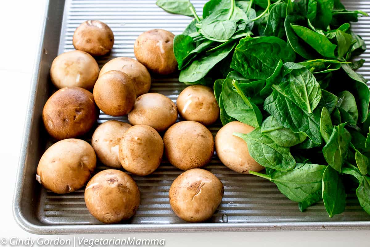 mushrooms and fresh spinach on a baking sheet