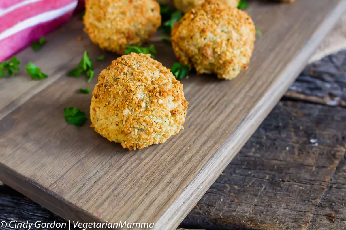 Air Fryer Risotto Balls on a gray wooden plank, garnished with chopped parsley. 