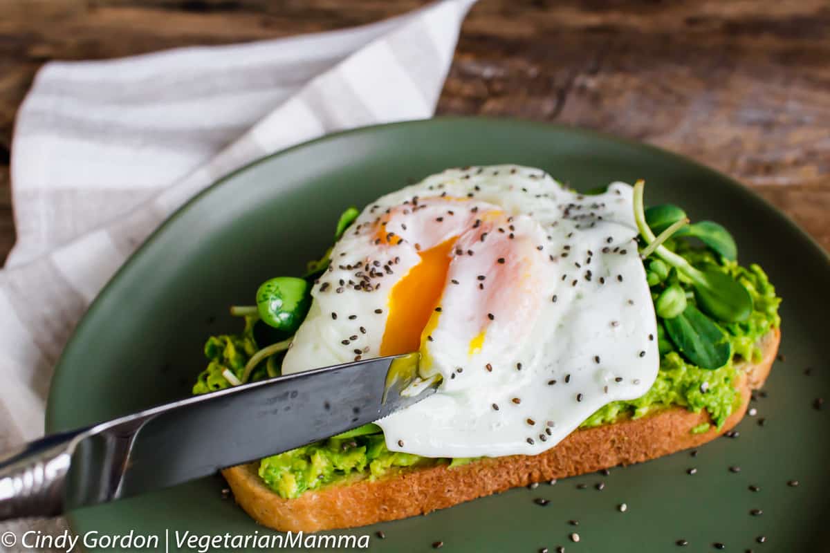 Knife cutting into fried egg avocado toast