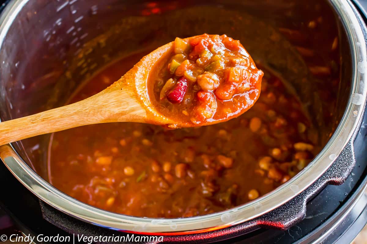 wooden spoon full of instant Pot Four Bean Chili dipped into an instant pot