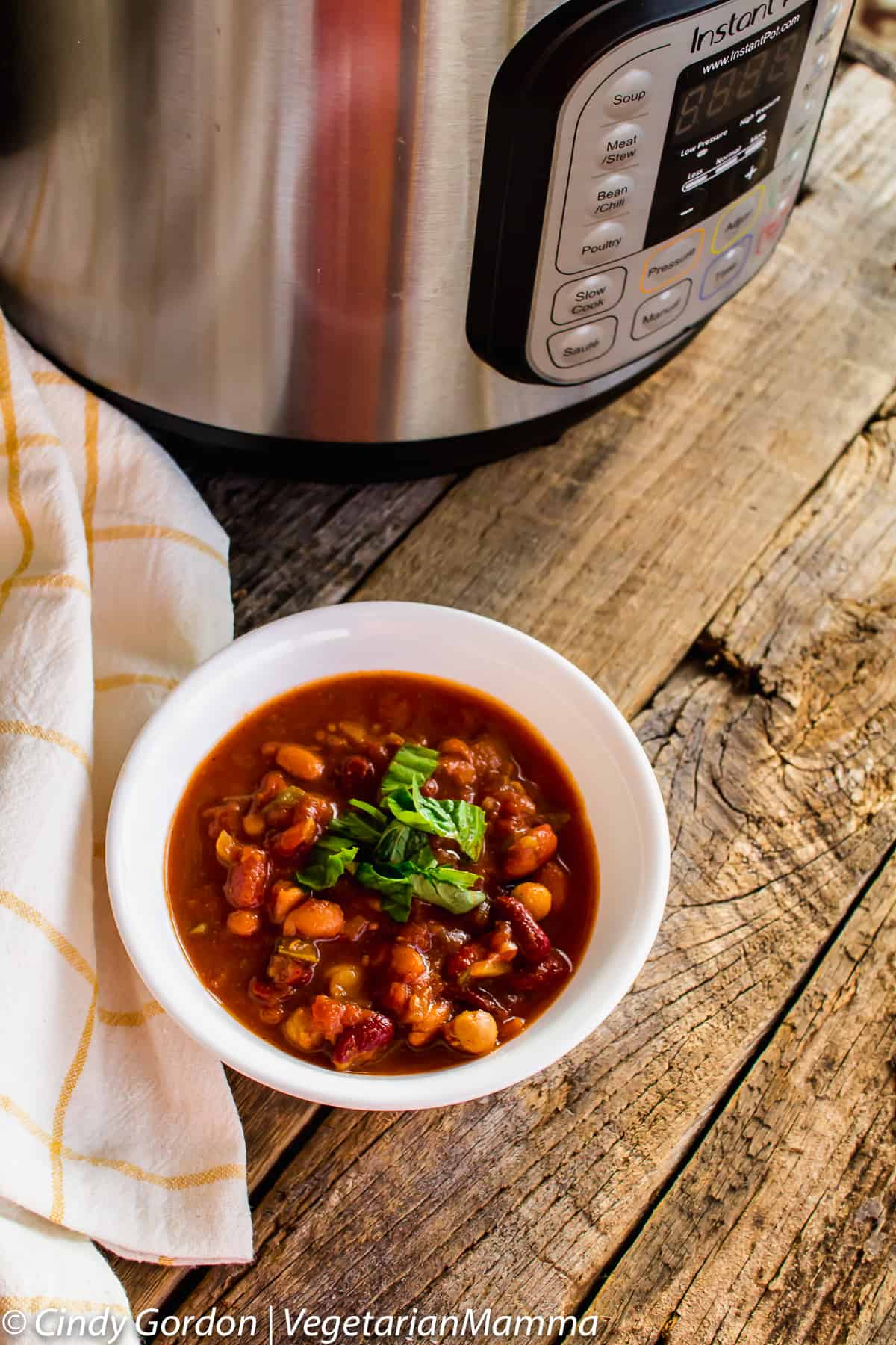 bowl of Instant Pot Four Bean Chili next to an instant pot