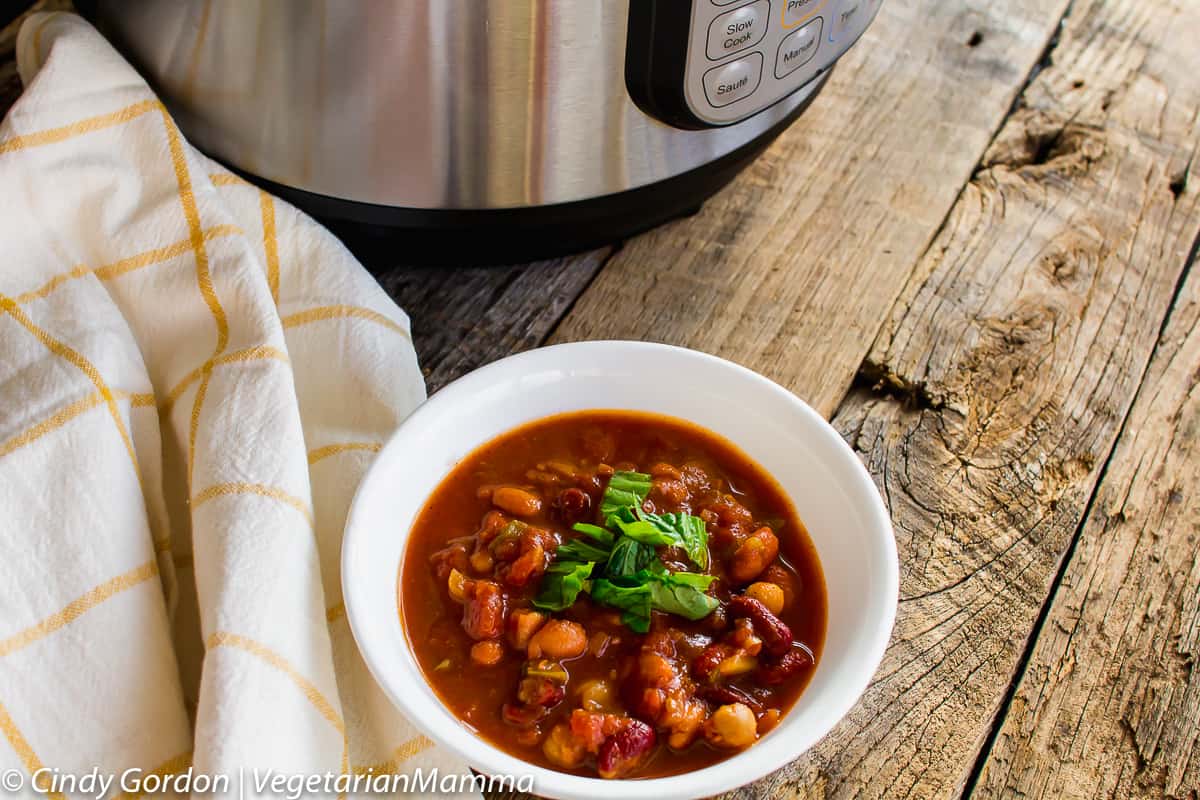 bowl of Instant Pot Four Bean Chili topped with fresh herbs 