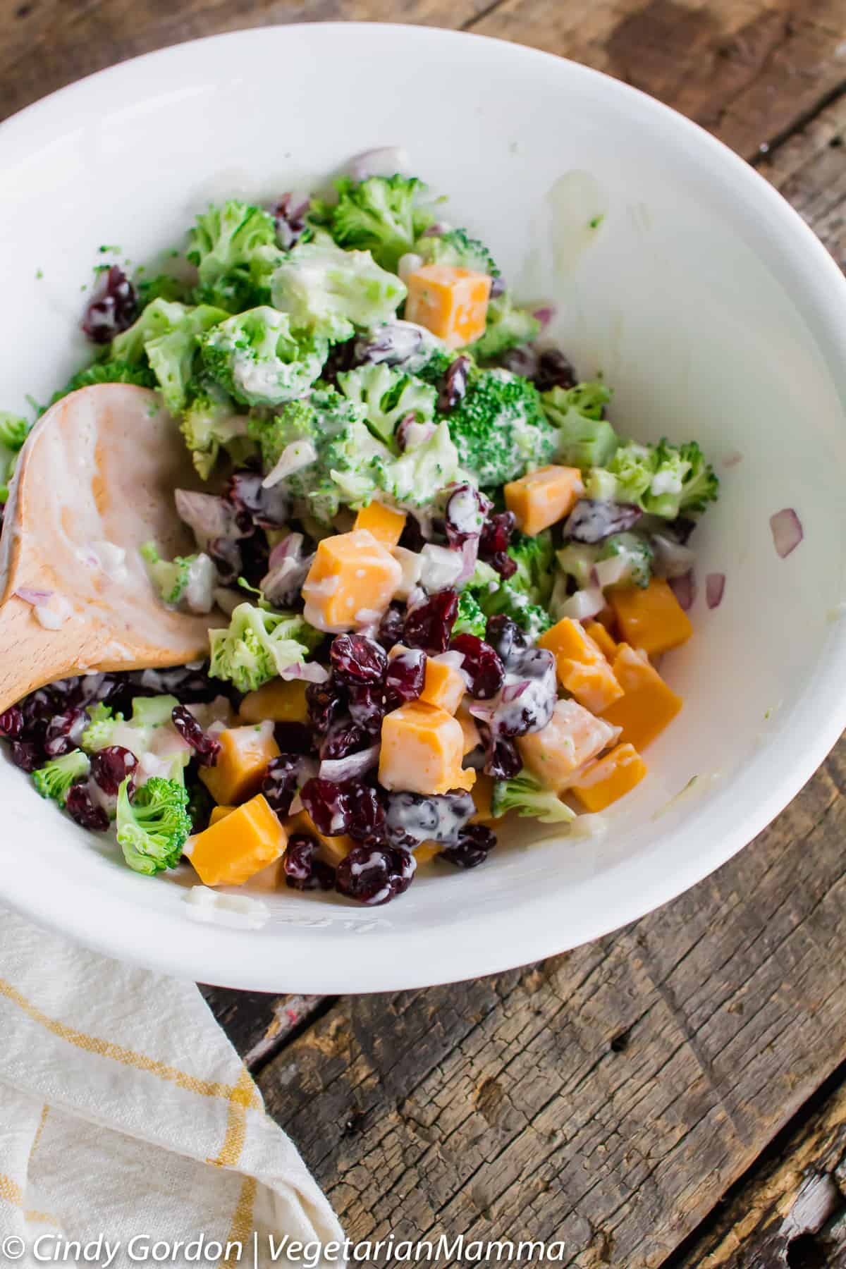 Broccoli salad with cheese, cranberries and a creamy salad in a white bowl. 