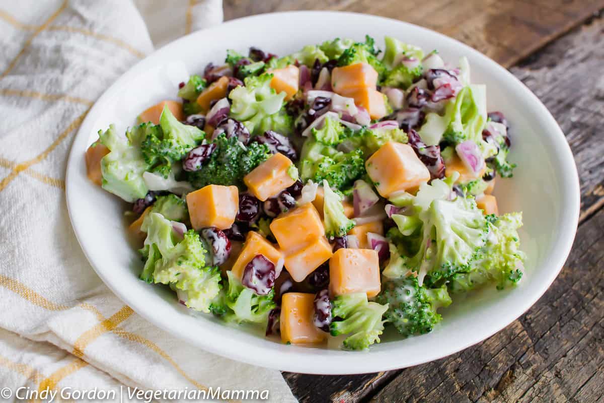 broccoli, cheddar cheese cubes, and cranberries in a creamy dressing in a white bowl.