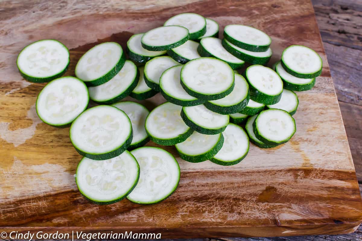 Raw Zucchini pieces resting on a wooden cutting board.