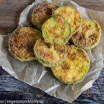 Crispy pan fried zucchini coins resting on parchment paper.