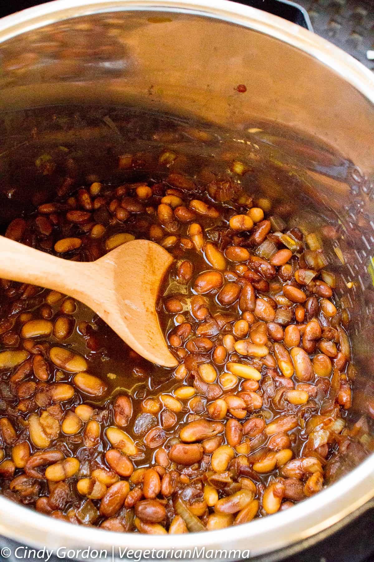 Instant Pot baked beans inside of an instant pot with a wooden spoon.