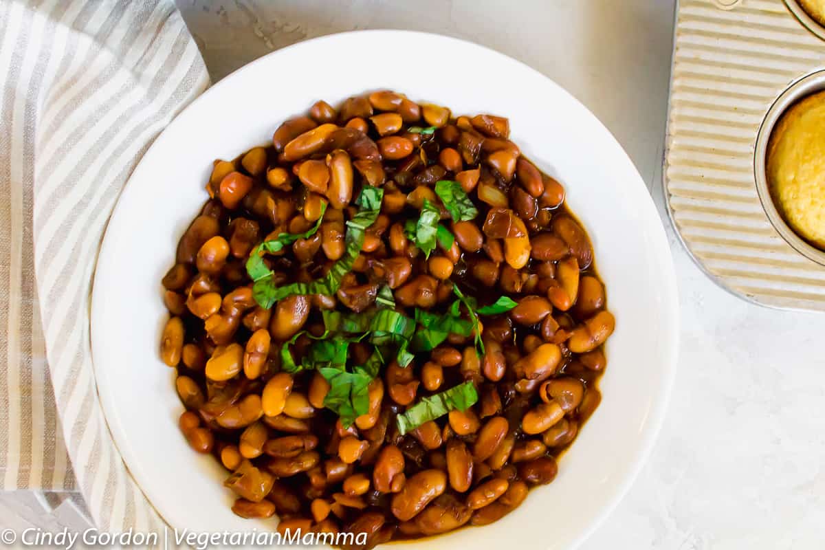 Instant Pot Baked Beans served in a white bowl with green basil garnish.