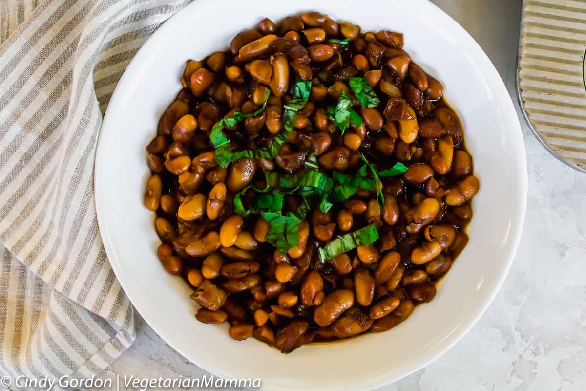 Vegetarian and gluten free instant pot baked beans with basil on top, served in a bowl.