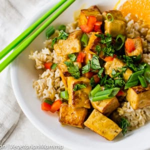 Orange Tofu in bowl with green chopstix to the side