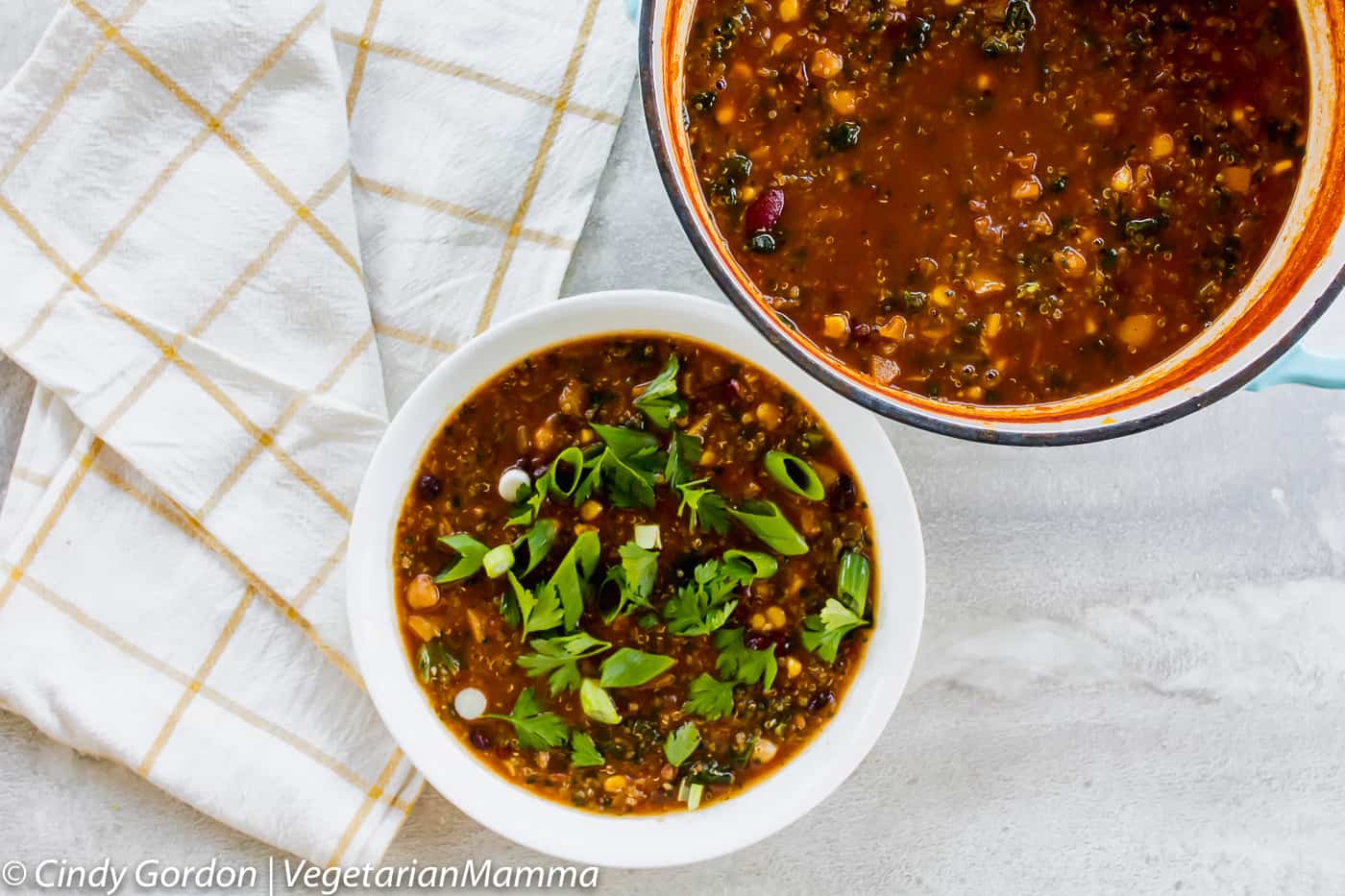 Pumpkin chili in two different bowls with white and yellow cloth beside bowls