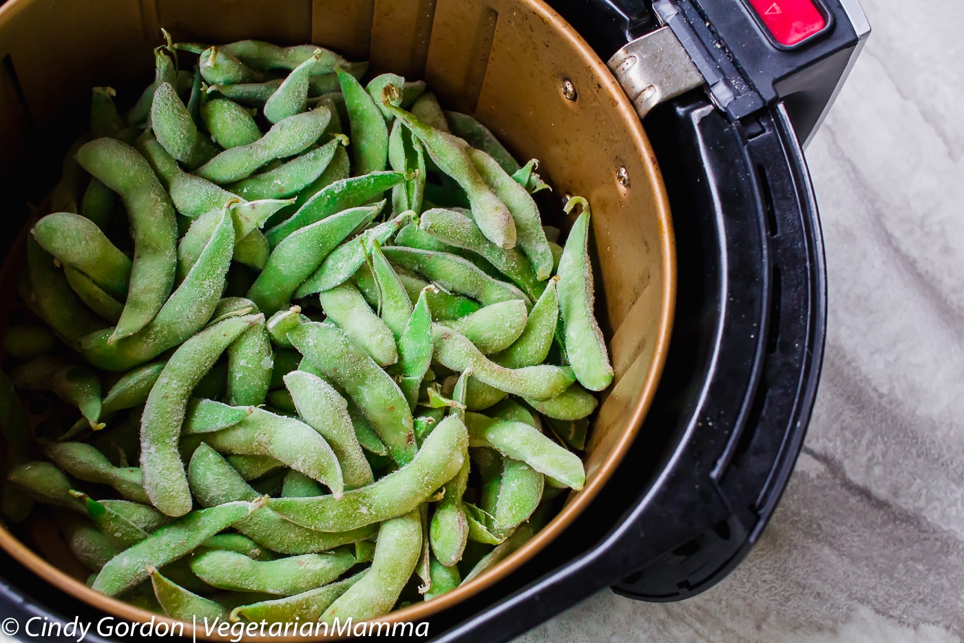 Frozen Edamame in the air fryer basket.