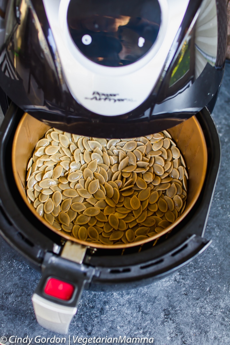 Air Fryer Pumpkin Seeds in the air fryer with basket open.