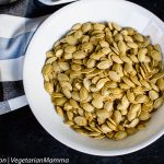 Top down view of pumpkin seeds inside of round white bowl