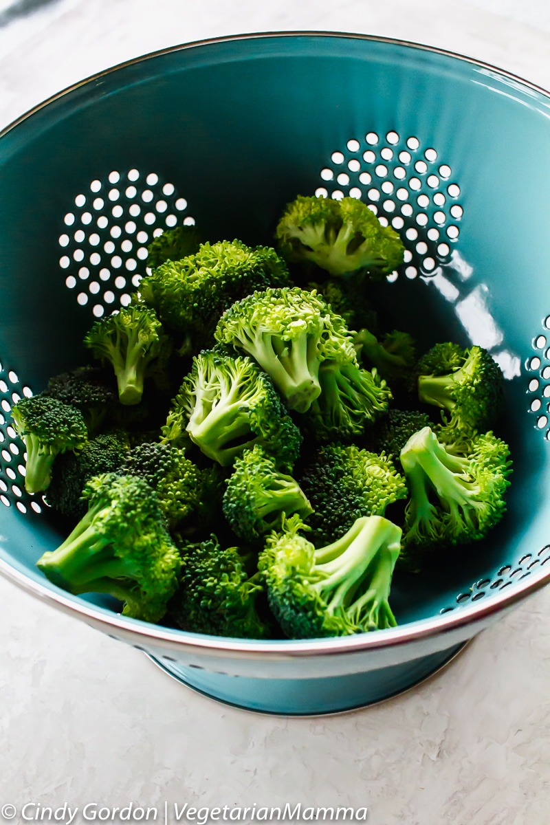 Air Fryer Broccoli - View of raw broccoli in blue strainer