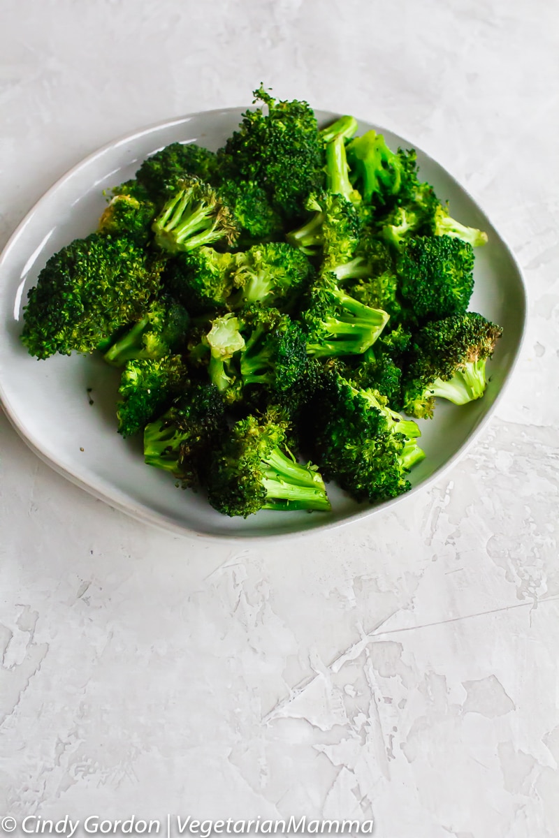 Air Fryer Broccoli on white plate with a white background