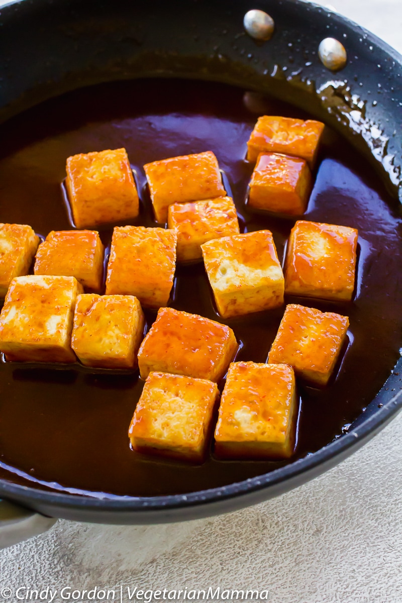 tofu cubes in sauce in a frying pan.
