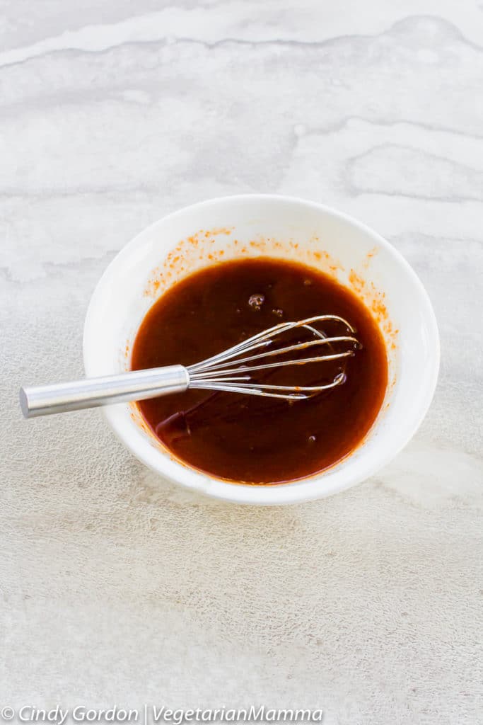Honey Sriracha Tofu sauce in a bowl with a whisk.
