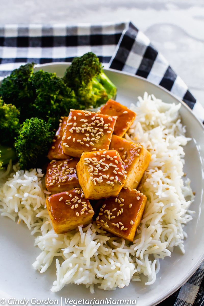 closeup view of honey sirracha tofu on top of rice and broccoli.