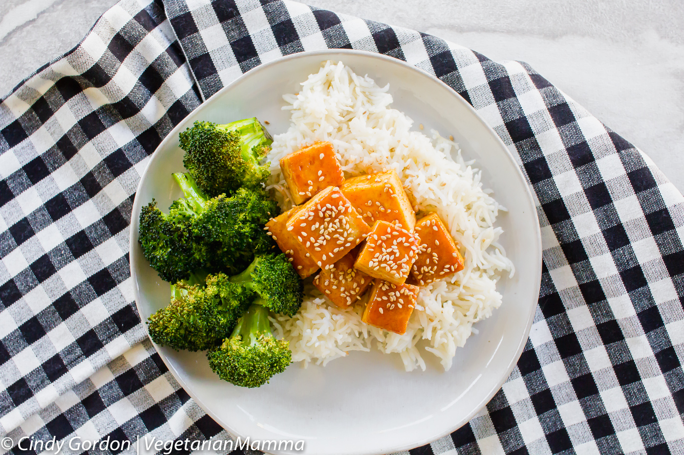 top down view of a plate of broccoli, rice, and tofu topped with sesame seeds