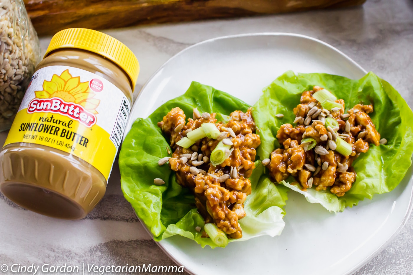 Two Thai Lettuce wraps on a plate next to a jar of SunButter