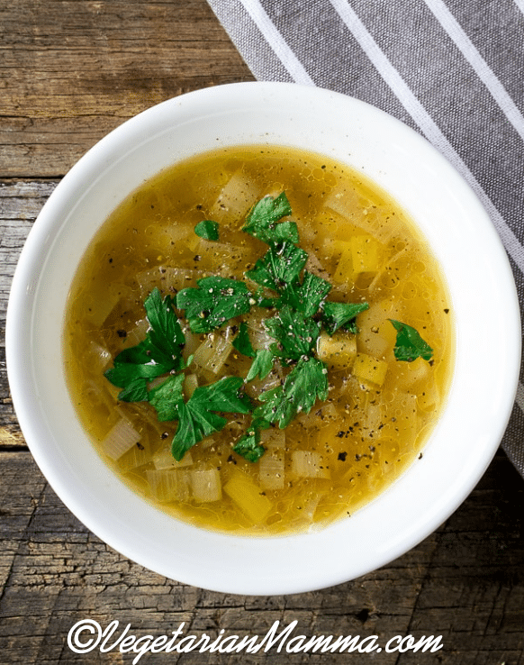 Instant Pot Potato Leek Soup in a white bowl atop a wooden pallet
