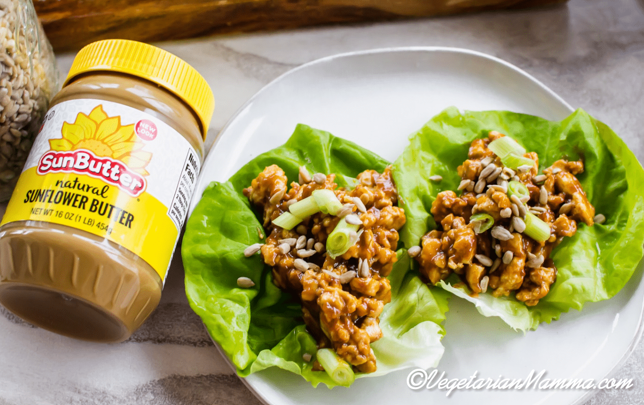 Two Thai Lettuce wraps on a plate next to a jar of SunButter