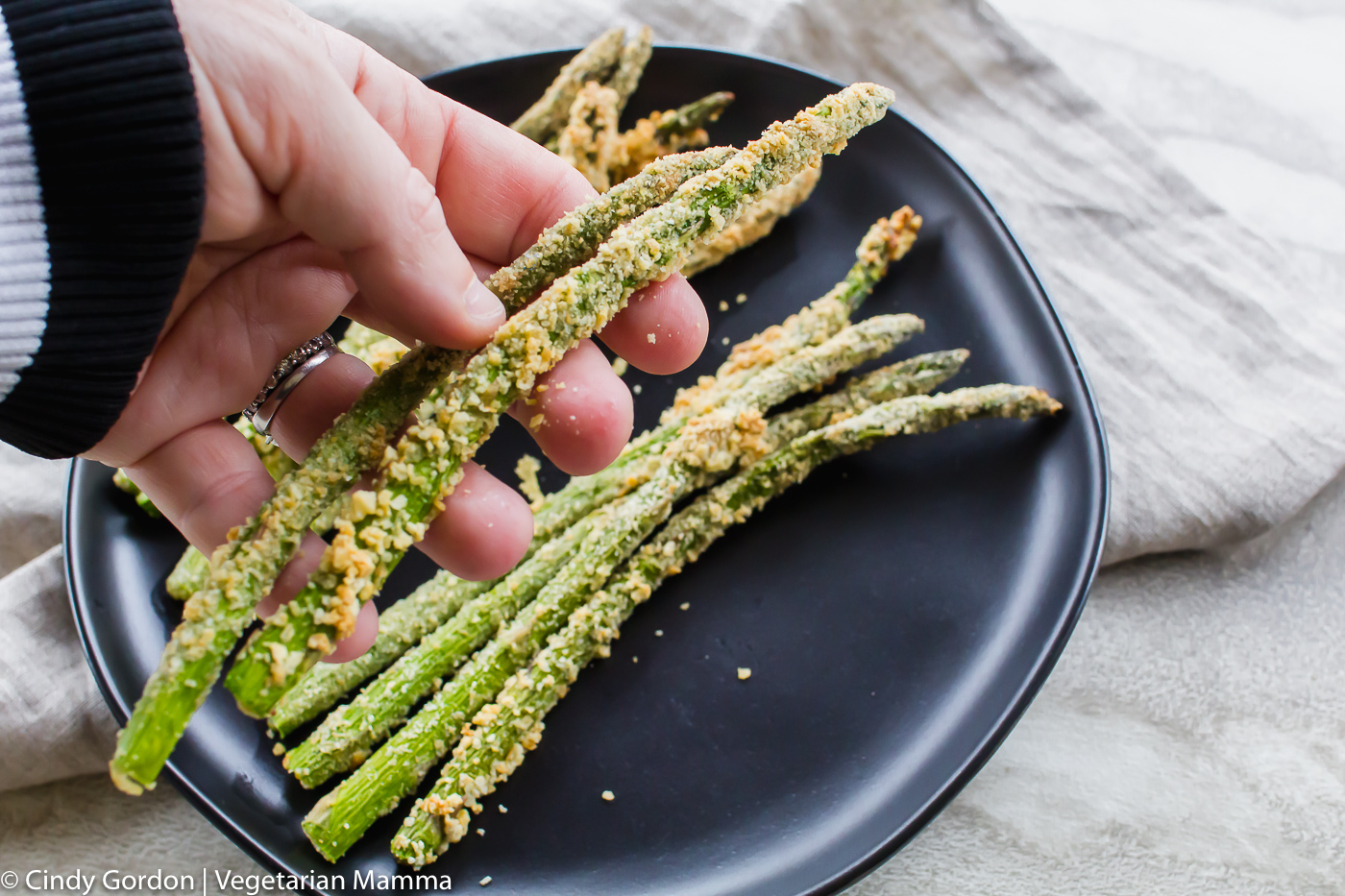 Hands holding Crispy Asparagus in Air Fryer 