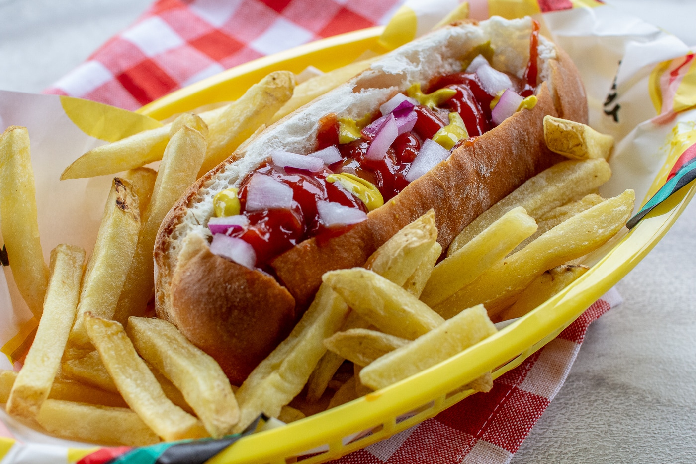 Air fried hot dog in bun topped with onion and ketchup