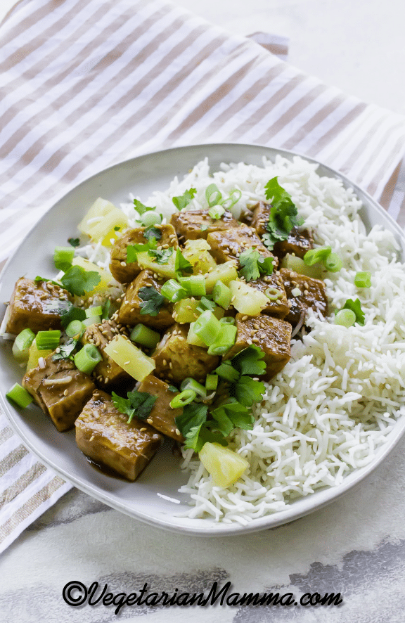 sweet and savory tofu with pineapple chunks on a plate of white rice. 