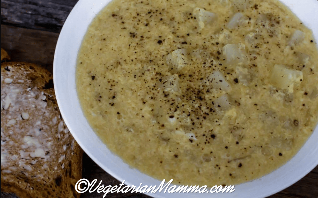 A white bowl of soup with a slice of bread on a wooden table. 