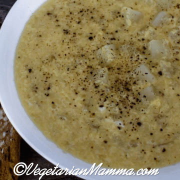 Bowl of soup in a white bowl on top a board.
