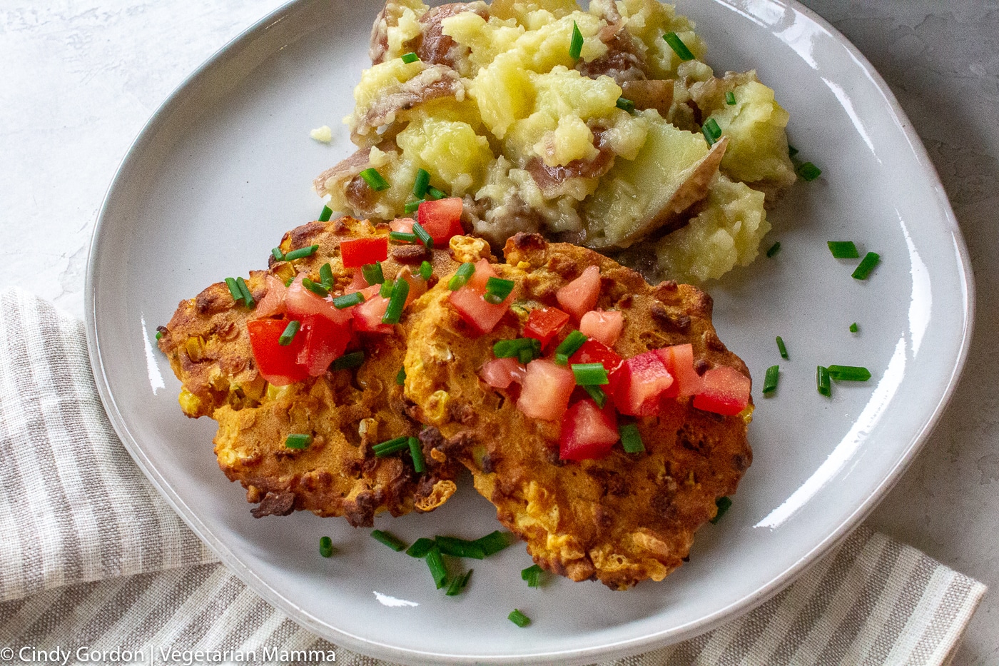Air Fryer Zucchini Fritters on white plate with mashed potatoes