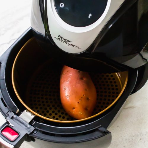 shot of an air fryer with a sweet potato in the air fryer basket