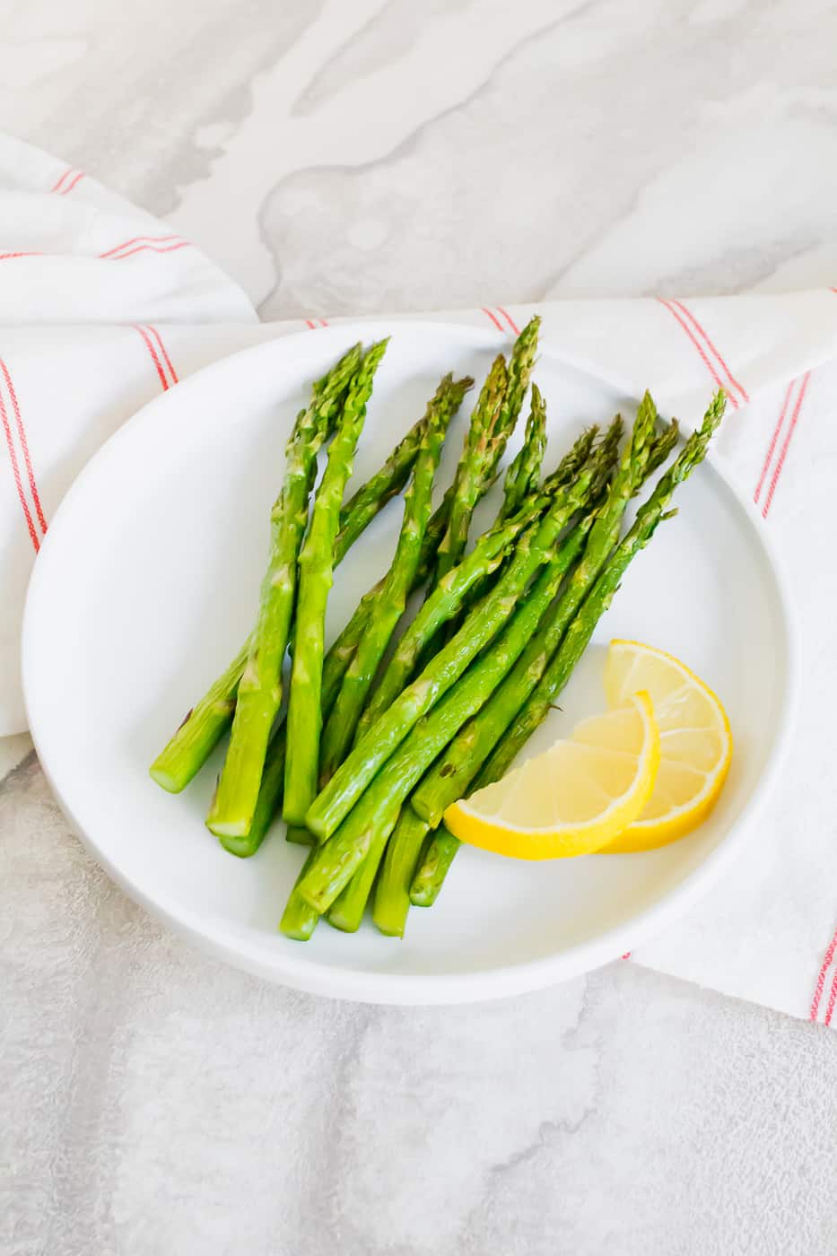 asparagus on a white plate with a yellow lemon cut in half