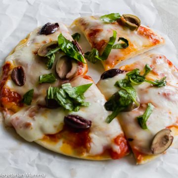 air fryer pizza cut into four pieces with fresh basil on top
