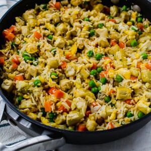 a black skillet filled with tofu fried rice and vegetables